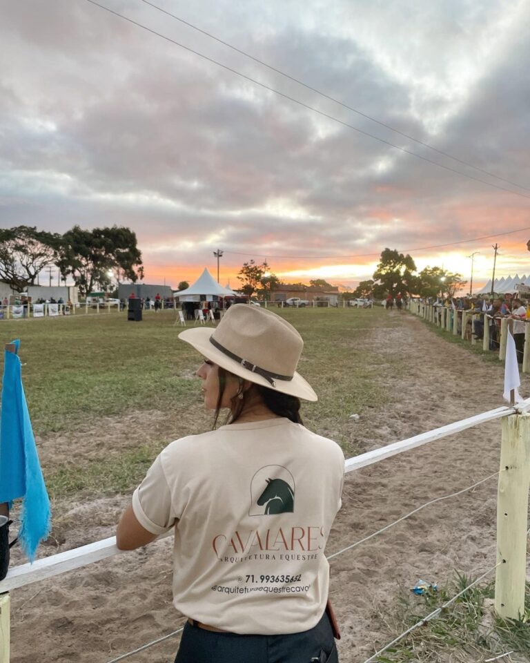 Profissional da Cavalares de camiseta e chapéu em evento equestre ao fim da tarde