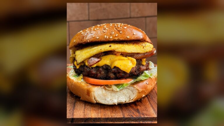 Hambúrguer artesanal com blend bovino, queijo e bacon, servido em tábua de madeira