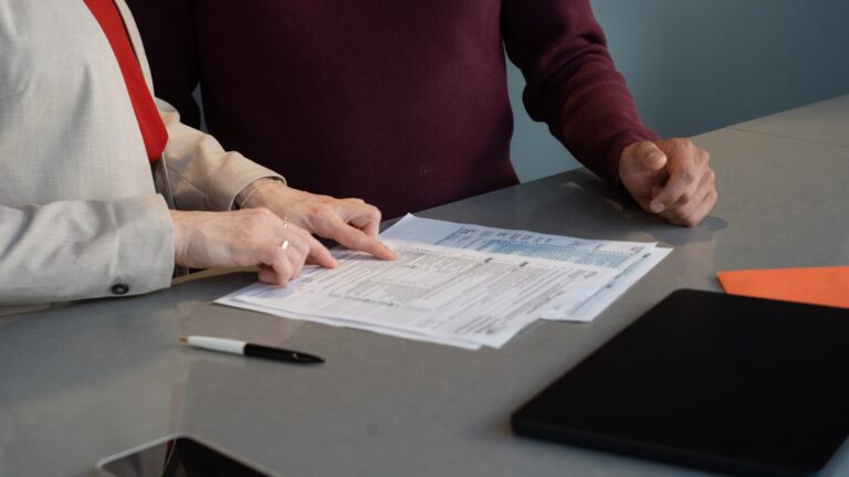 Duas pessoas conferindo documentos sobre uma mesa