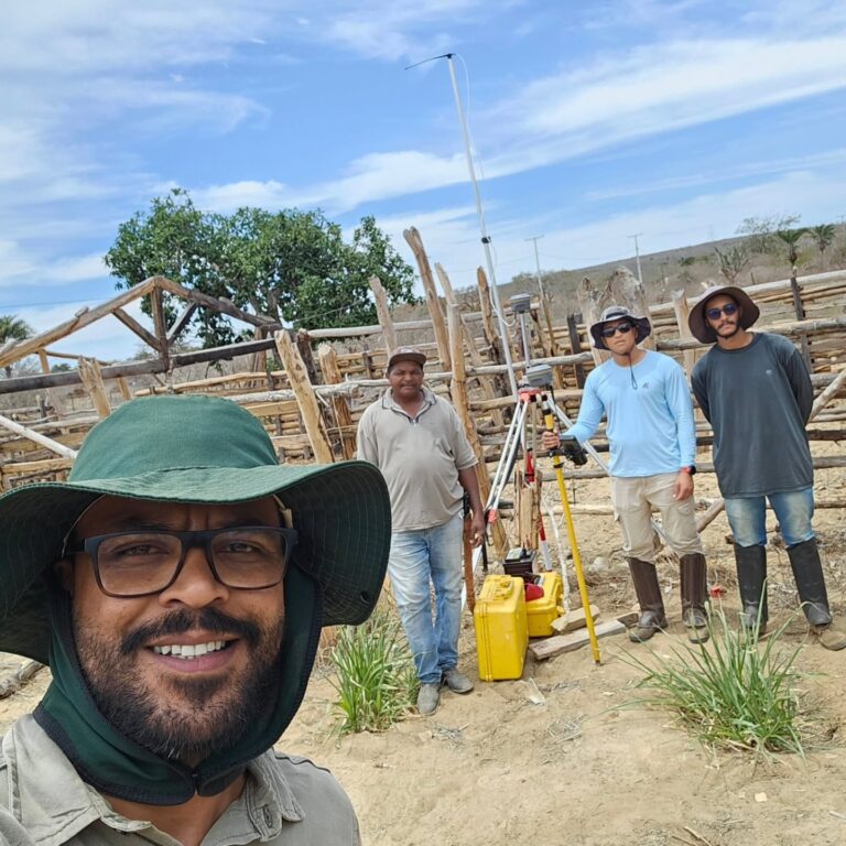Selfie da equipe da Ventura Engenharia em levantamento de campo, perto de uma cerca de madeira