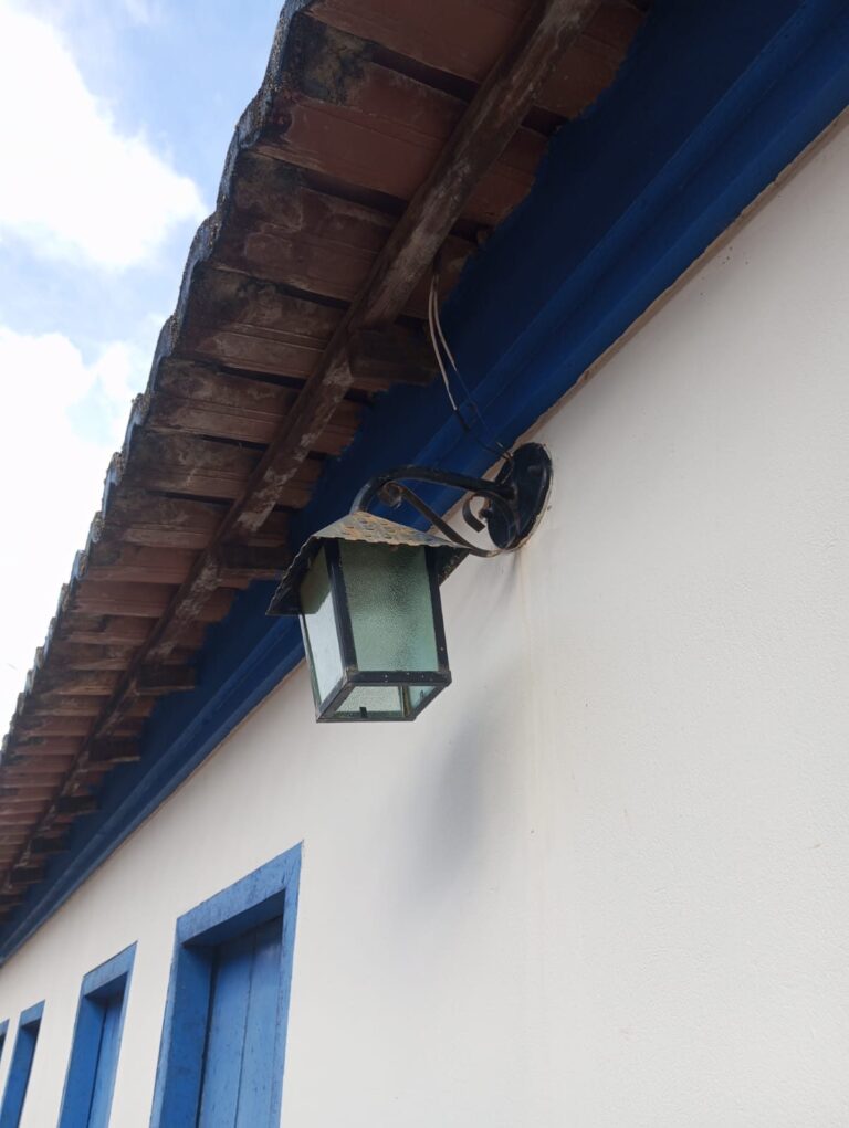 Beiral de telha com barra azul e lanterna de ferro numa casa branca da Vila do Ventura