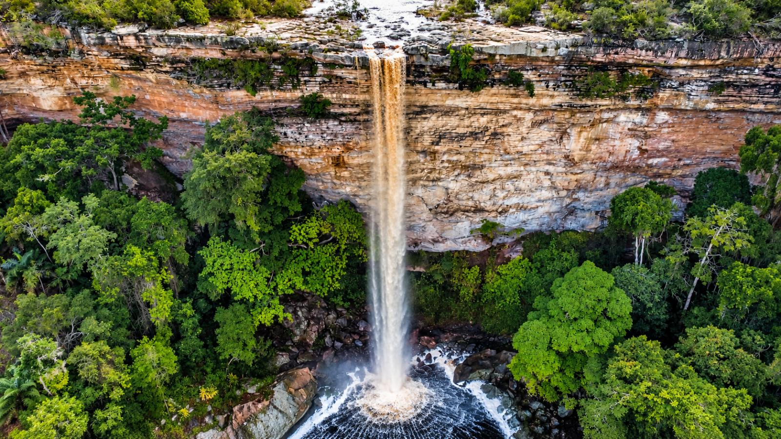 Vista aérea da Cachoeira do Ventura cercada de mata verde, com a água caindo num poço
