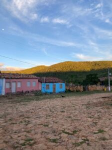 Casas térreas coloridas da Vila do Ventura diante da serra, com a rua de terra em primeiro plano