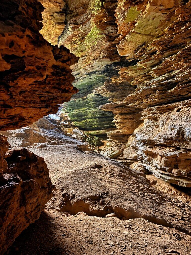 Paredes de rocha em camadas com manchas verdes dentro da Gruta do Cristal