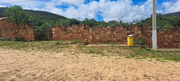 Rua de pedra da Vila do Ventura com muro de pedra ao fundo e a serra coberta de mata atrás
