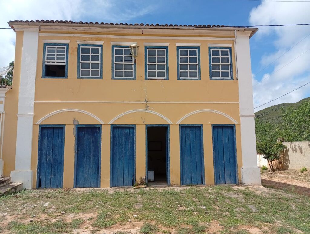 Fachada de sobrado amarelo de dois andares na Vila do Ventura, com seis portas azuis embaixo e seis janelas em cima