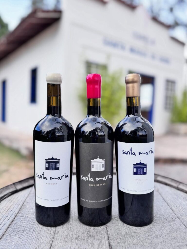 Três garrafas de vinho da Santa Maria diante da capela