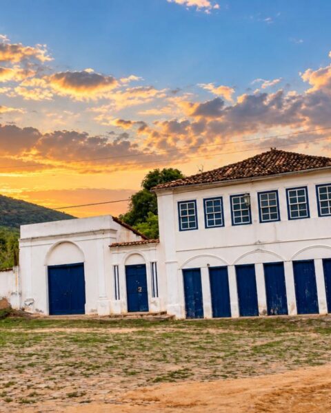Casarão branco de janelas azuis na Vila do Ventura, em Morro do Chapéu, ao entardecer