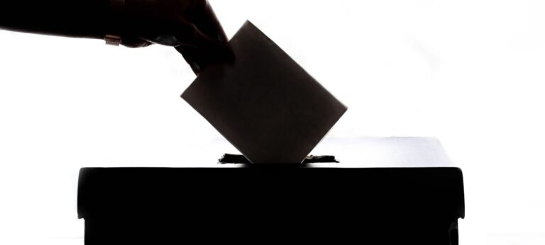 Silhueta de uma mão colocando o voto na urna