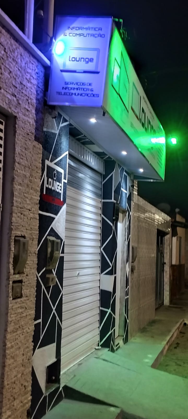 Placa azul e letreiro da Lounge Informática na entrada da loja, em Morro do Chapéu