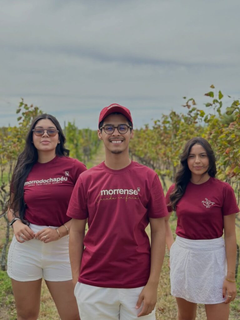 Três pessoas vestindo camisetas vinho Morrense da Made in Morro em um vinhedo